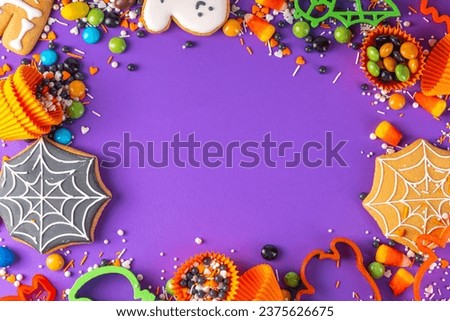 Bright colorful Halloween gingerbread cookies and sweet background. Homemade biscuits with cookie cutters, sugar sprinkles and candies. High-colored Halloween treats flat lay top view copy space