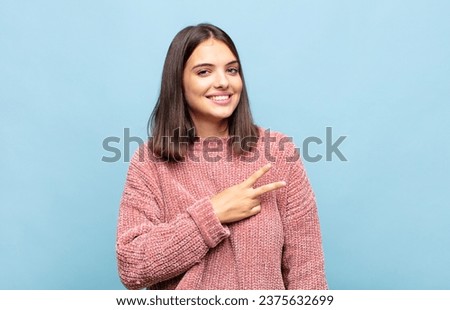 young pretty woman feeling happy, positive and successful, with hand making v shape over chest, showing victory or peace Royalty-Free Stock Photo #2375632699