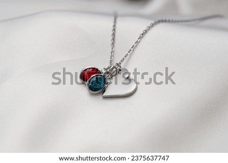 satin on a white plate and marble on a wooden background silver gold jewelry with colored stones round and heart