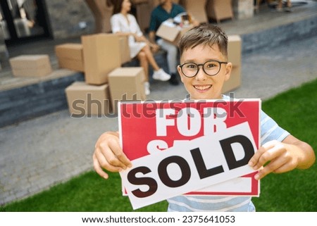 Happy boy holding for sale, sold signs in his hands