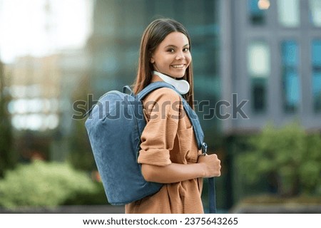 Young woman student with backpack walking through campus. Joyful pretty lady posing at university park, exuding positivity and a thirst for knowledge amidst an atmosphere of academic pursuit Royalty-Free Stock Photo #2375643265