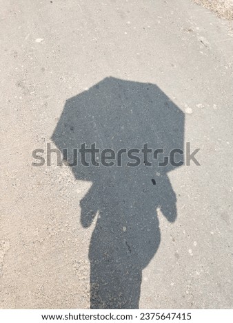 The shadow of a human being with an umbrella on the head casts a striking and enigmatic silhouette.The shadow portrays a sense of preparedness and resilience.This image evokes a sense of mystery also.