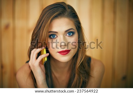 Smiling woman talking phone. Beautiful girl face portrait with evening make up on wooden background.