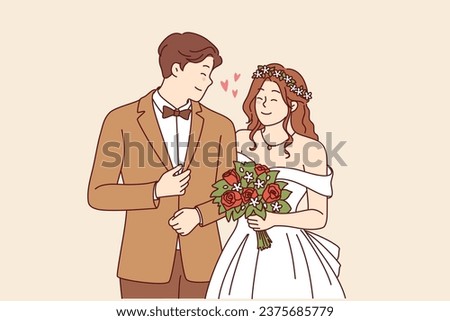 Wedding ceremony at bride and groom in beautiful outfits holding hands during engagement in church. Woman with bouquet flowers stands near husband at wedding ceremony, posing together for family photo Royalty-Free Stock Photo #2375685779