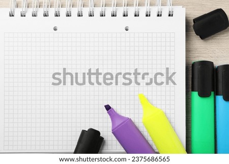 Empty notebook and colorful markers on wooden table, flat lay
