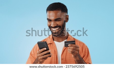 Man, credit card and excited with phone, studio and thinking of sale, promo code or info by blue background. Online shopping, easy payment and happy for financial freedom, fintech app or smartphone
