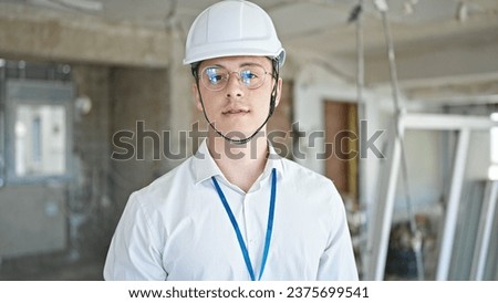 Young hispanic man architect standing with relaxed expression at construction site