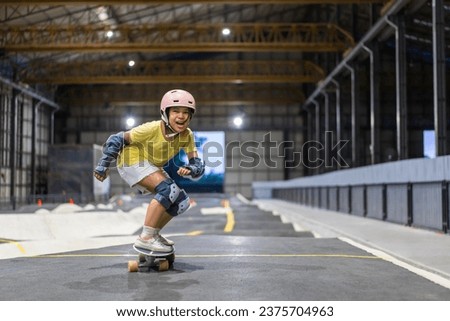 asian child skater or kid girl fun playing skateboard or smile ride surf skate in pump track at skate park to happy winner on finish line by extreme sports surfing to wears helmet guard body safety Royalty-Free Stock Photo #2375704963