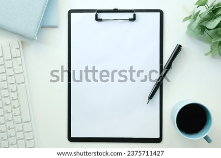 White office desk table with blank notebook, computer keyboard and other office supplies. Top view with copy space, flat lay..