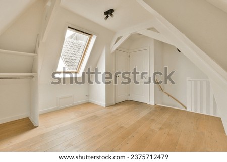 an empty room with wood flooring and skylights on the top of the attic loft windows are visible in the photo Royalty-Free Stock Photo #2375712479