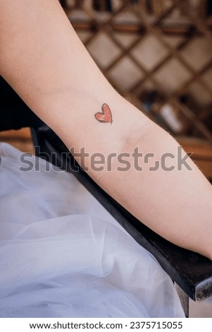 Wearing your heart on your sleeve, simple drawing of red heart on girl's arm Royalty-Free Stock Photo #2375715055