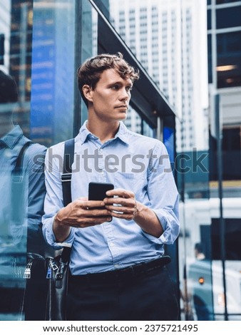 Handsome elegant man standing holding bag and smartphone on street
