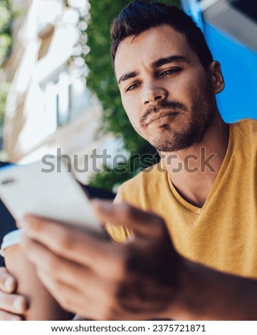 Young man drinking takeaway coffee and using smartphone on street