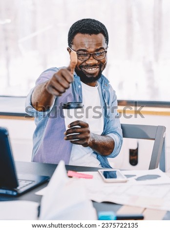 Man showing thumb up while sitting at table