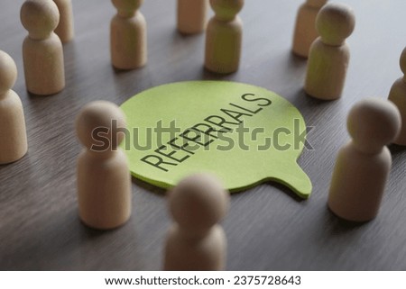 A group of wooden figurines surrounding a speech bubble with text REFERRALS. Recommendation, marketing, customer retention and loyalty concept Royalty-Free Stock Photo #2375728643
