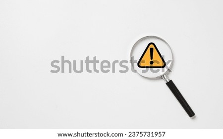 Black and yellow triangle caution warning sign inside of magnifier glass for notification error and maintenance concept.