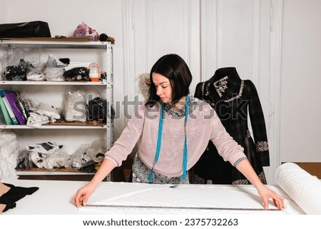 Seamstress works in the tailoring workshop with fabric and tools on the table