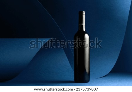 Bottle of red wine on a blue background. Copy space.