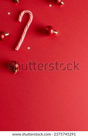 Vertical image of christmas baubles decorations and candy canes with copy space on red background. Christmas, decorations, tradition and celebration concept.