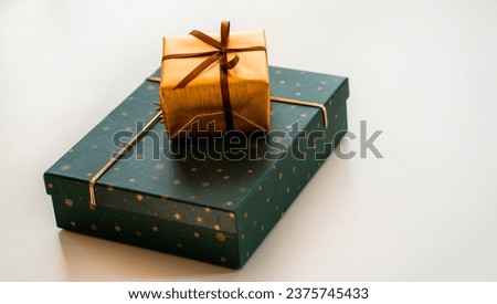Beautifully wrapped gifts in gold and green colors lie on a light surface, on the table. Purchased surprises for birthdays, New Years, and Christmas are prepared for the holidays.