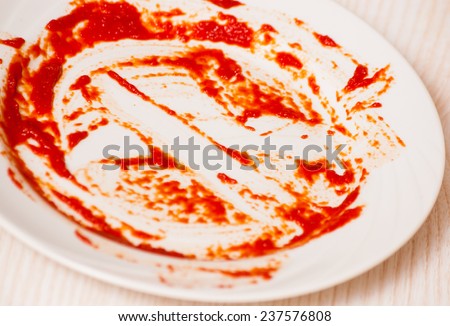 Dirty plate on the table. Tomato sauce smeared on a plate.
