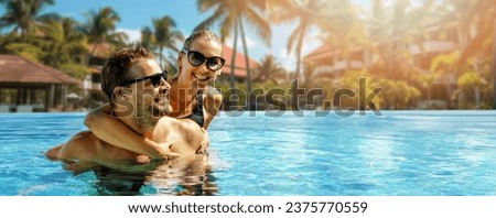 smiling happy couple having fun together in resort swimming pool. summer vacation, getaway travel. banner with copy space Royalty-Free Stock Photo #2375770559