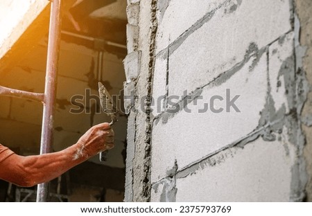 Hands of worker plasterer pillar cement construction with trowel, man at work by plastering a wall of construction site.Home renovation and building new house. Royalty-Free Stock Photo #2375793769