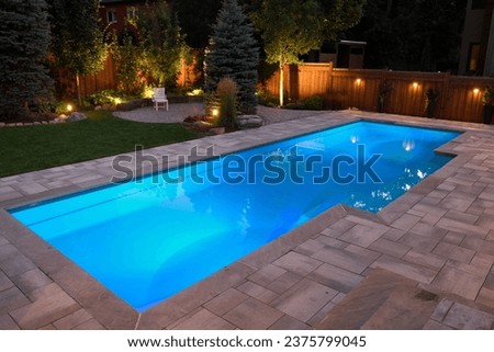 Lights in swimming pool and backyard patio and deck at night Royalty-Free Stock Photo #2375799045