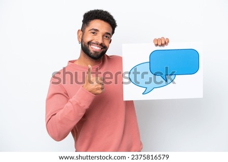 Young Brazilian man isolated on white background holding a placard with speech bubble icon with thumb up