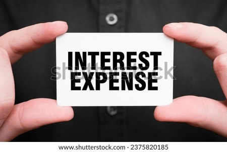 Businessman holding a card with text interest expense , business concept