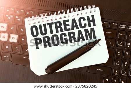 White paper sheet with text OUTREACH PROGRAM on the black laptop Royalty-Free Stock Photo #2375820245