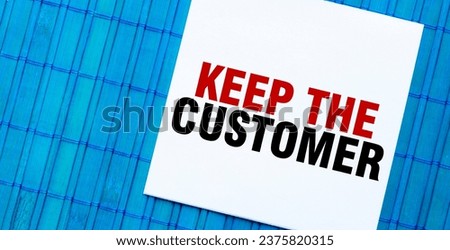 blank note pad with KEEP THE CUSTOMER text on blue wooden background