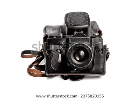 Old film SLR camera in a worn leather case on a white background, floating focus, slight noise