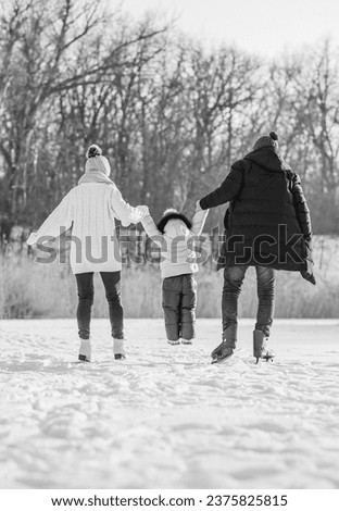 Young parents and a little daughter skate on a frozen river in a park in winter. Christmas, family and holiday concept.