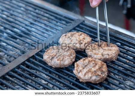 Chef making burger meat at the open air restaurant grill. Festival food, fast food restaurant , cooking meatballs on the grill with tongs in hand. High quality photo
