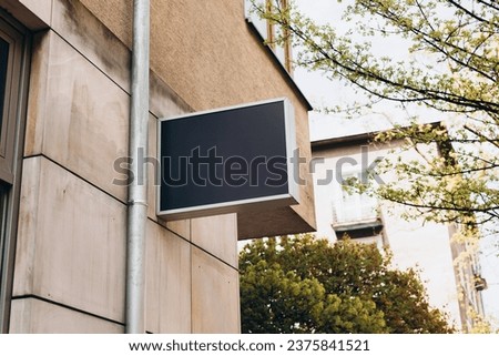 Blank sign mockup in the urban environment. Black rectangle sign with blank space for cafe or restaurant name and logo