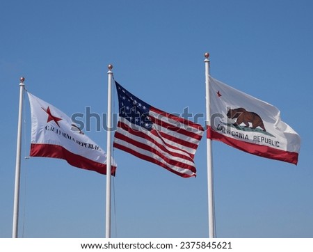 Flags of California and the United States of America against a clear blue sky seen at Stearns Wharf in Santa Barbara, California, USA