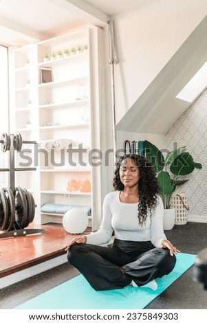 Attractive black woman meditating at home gym 