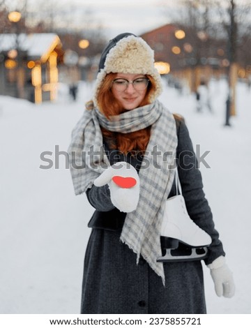 young beautiful woman is holding red card in form of heart, Valentine's day, Valentine's Day. happy woman in life clothes walks in park on date and enjoys life. Winter holidays love freedom