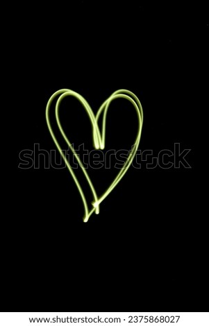 Yellow heart of neon light, abstract lines in the dark, long exposure technique photography, smooth golden lines, no people