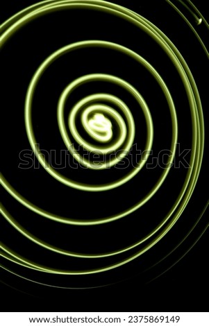 Yellow swirl made of neon light, fine lines against dark background, no people, yellow circle, long exposure technique photography