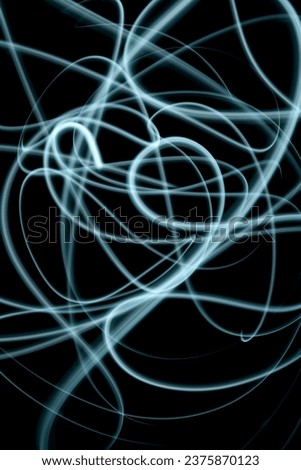 Abstract blue light in the dark, abstract long exposure photography technique, fine lines of light, messy blue lines against dark background, no people