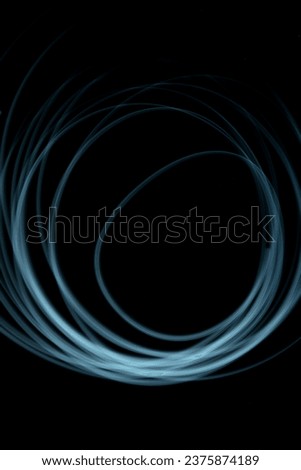 Neon light round shapes against dark background, long exposure technique photography, modern lines of light, abstract shapes, blue swirl, blue circle of light
