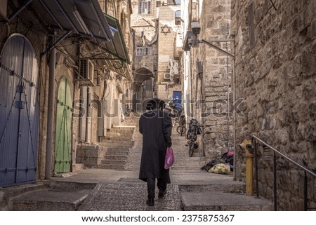 The Haredi (ultra-Orthodox) Jewish man is walking down the empty street in the old  city of Jerusalem in Israel. Royalty-Free Stock Photo #2375875367