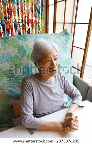 Senior woman with gray hair sitting on a reclining nursing bed and staring straight ahead