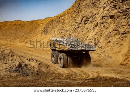 The tires on mining trucks are enormous to distribute the weight of the massive payloads they carry and provide stability and traction on rough terrain. Royalty-Free Stock Photo #2375876535