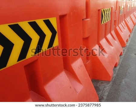close up of orange road barriers lining the side of the road
