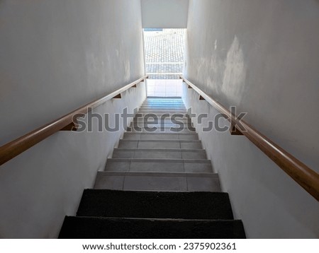 Photo of a hallway with stairs with iron railings attached to a white wall 