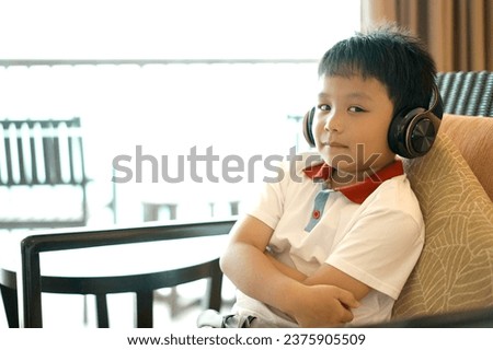 Little happy boy wearing headphones listen to music dance at the sea view.  Lifestyle concept.