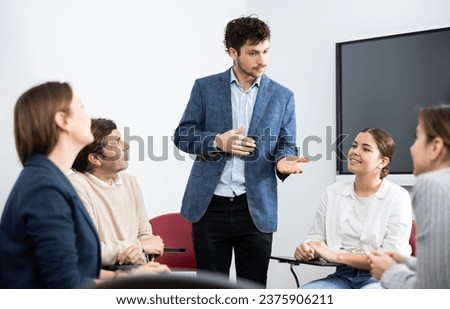 Young male tutor teaching students in college classroom Royalty-Free Stock Photo #2375906211